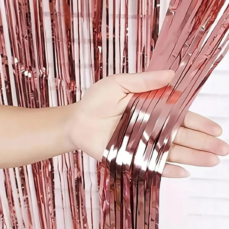 Zbliżenie na przygotowywanie dekoracji urodzinowej na tle błyszczącej kurtyny foliowej Rose Gold.